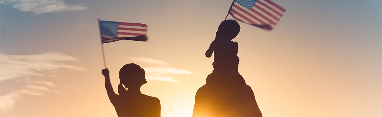 A family waving American flags at sunset